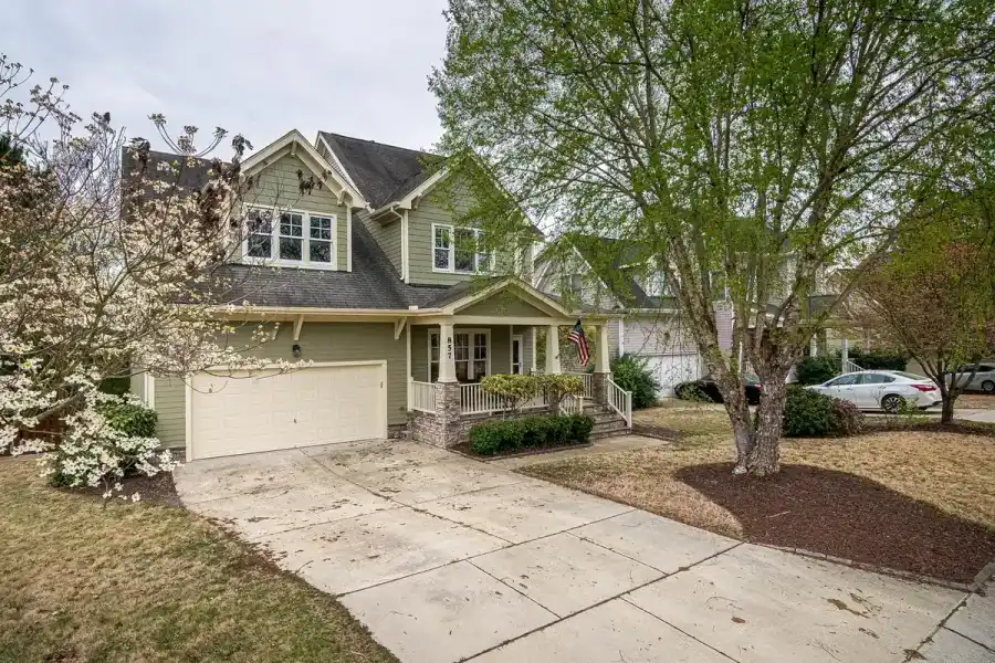 Suburban house and driveway shaded by a large established front-yard tree