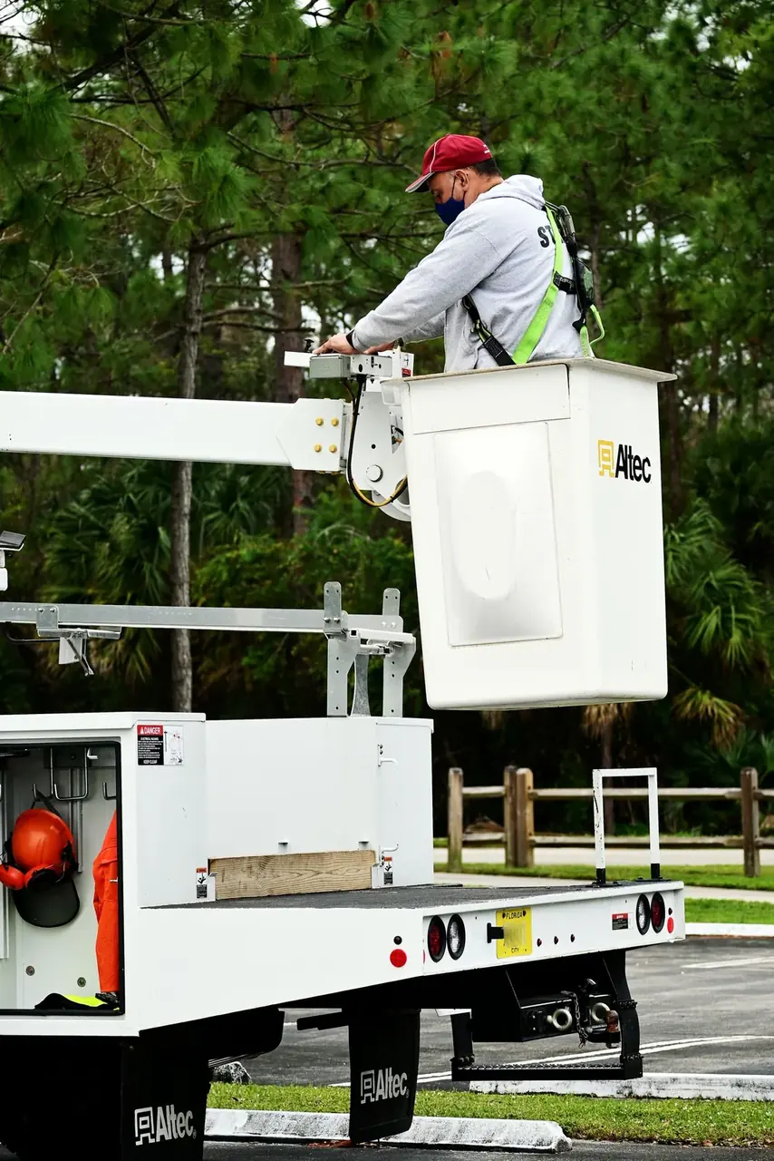 White aerial lift bucket truck with its boom raised and a technician working from the elevated platform